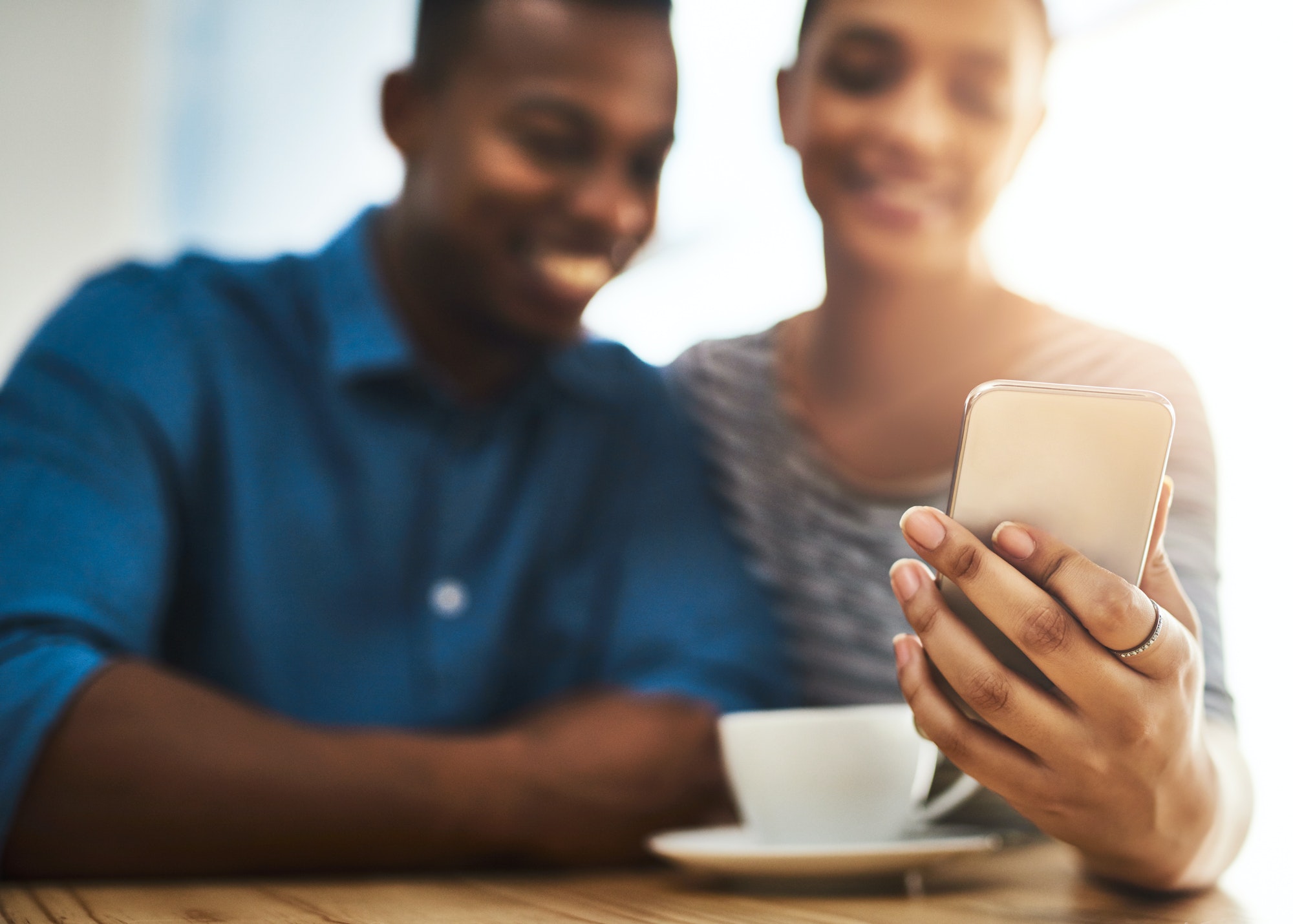 Shot of a young man and woman using a mobile phone together on a date at a coffee shop